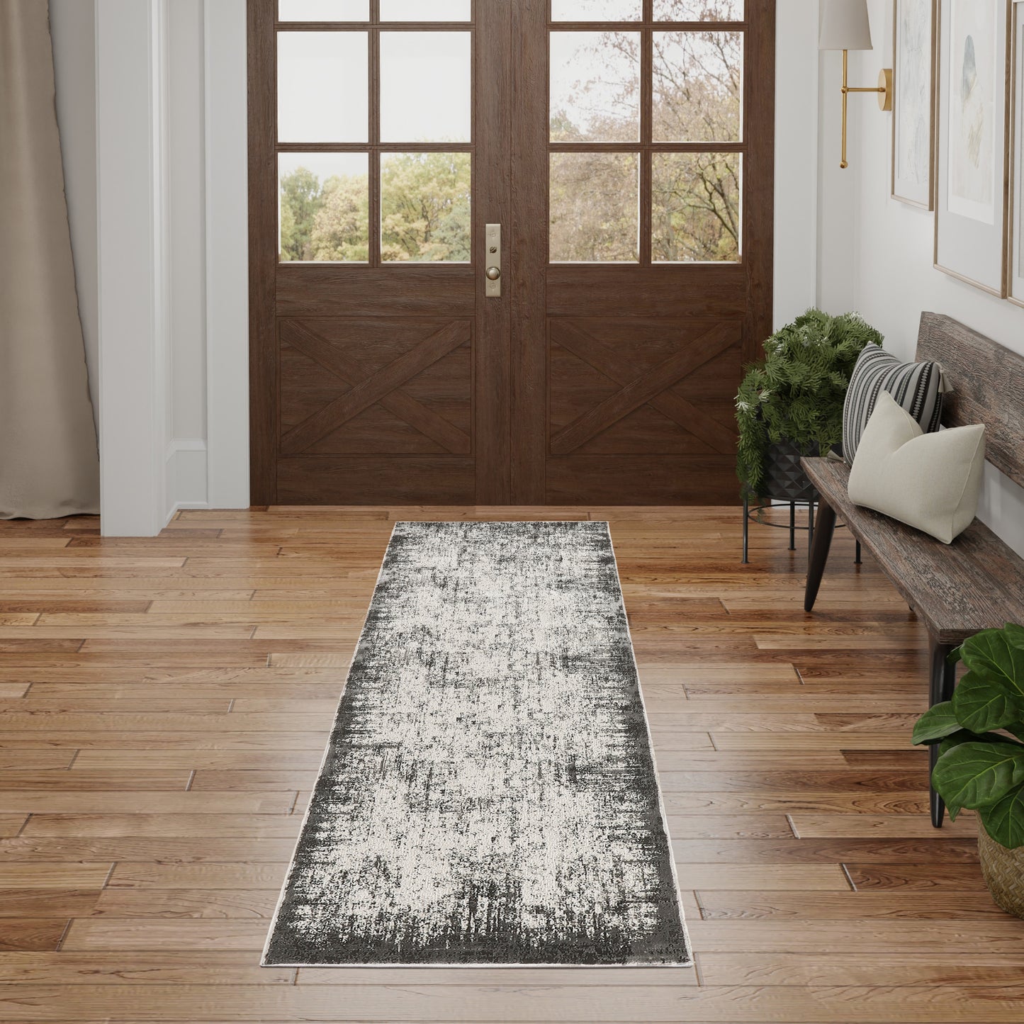 Dark wood double entry doors with grid glass panes; long gray distressed runner rug on oak hardwood, bench and greenery.