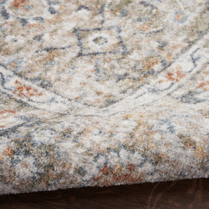 Close-up of a plush Persian-inspired rug with beige, blue-gray and orange motifs on a wooden floor.