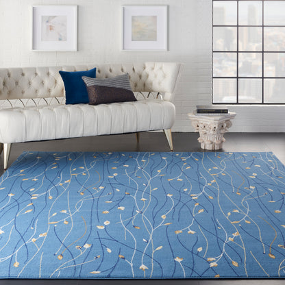 Blue area rug with cream botanical pattern in a modern living room with a tufted ivory sofa.