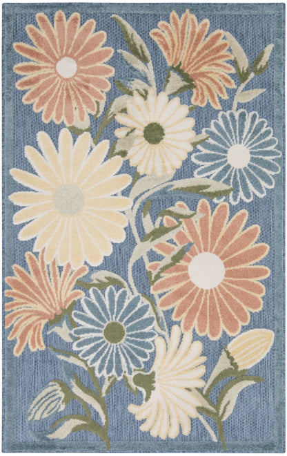 Area rug with large pastel daisies on a denim-blue background; peach, cream, yellow, and blue petals with green stems.