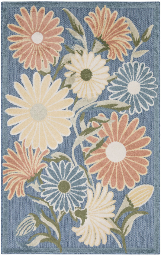 Area rug with large pastel daisies on a denim-blue background; peach, cream, yellow, and blue petals with green stems.