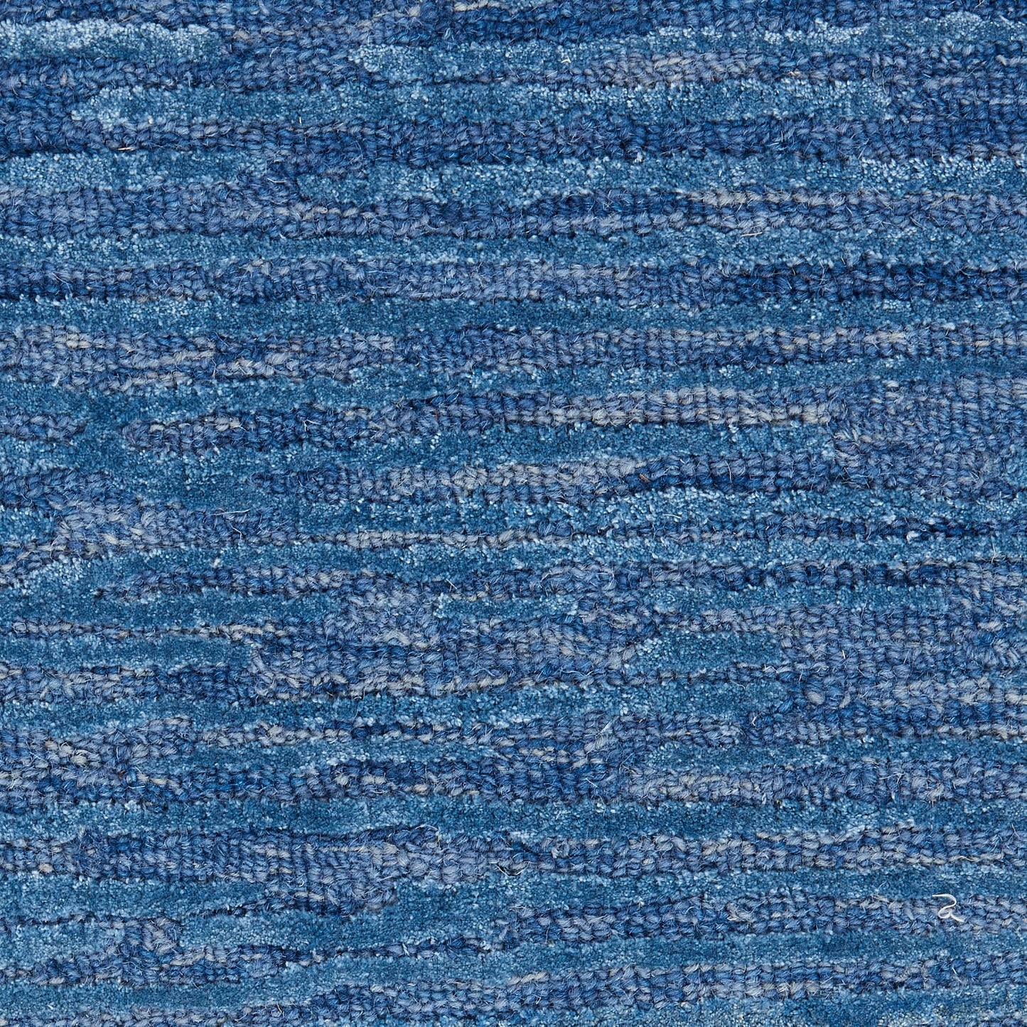 Blue textured woven rug with variegated indigo tones and loop-pile texture.