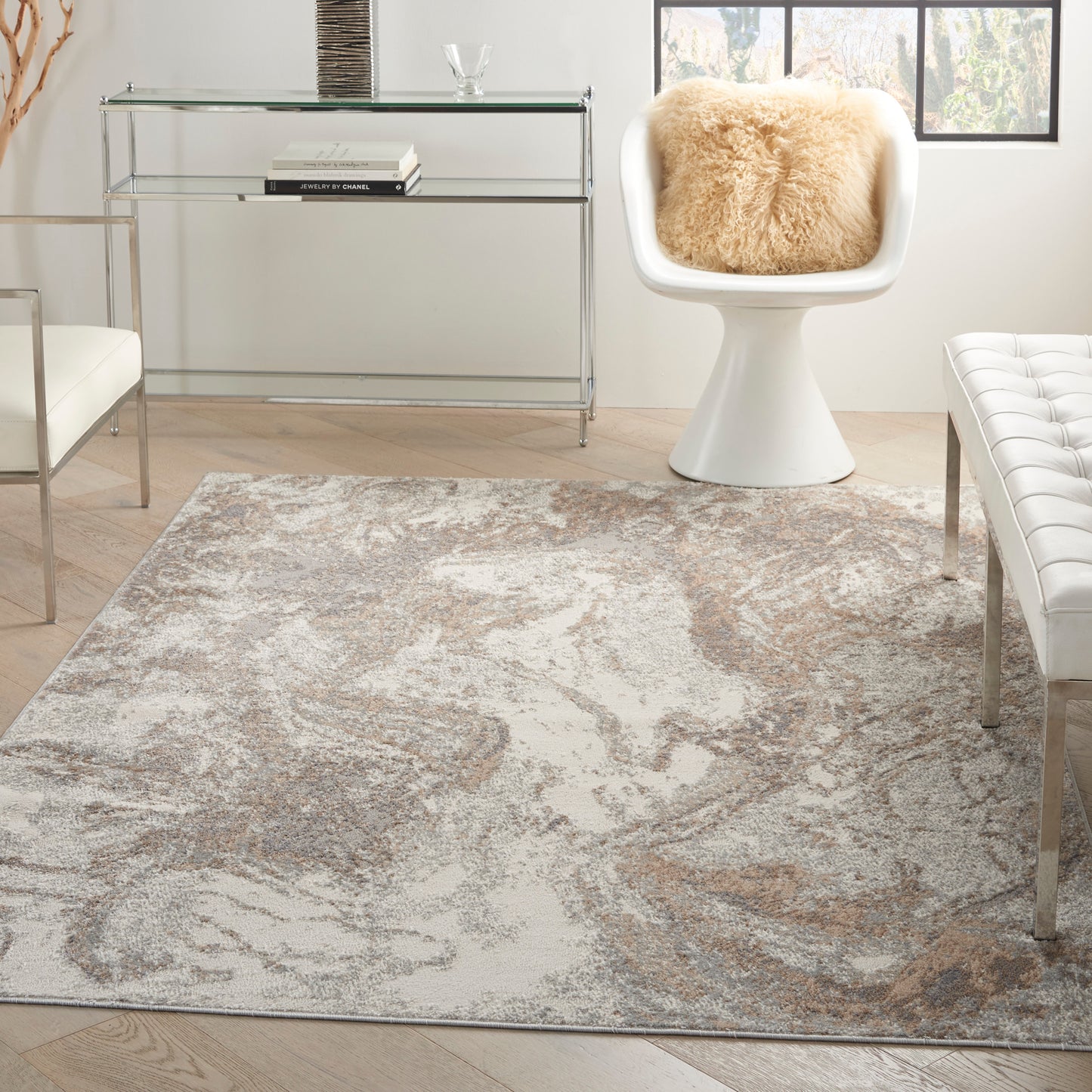 Modern living room with abstract beige-gray rug, glass chrome console table, white curved chair with fluffy beige cushion.