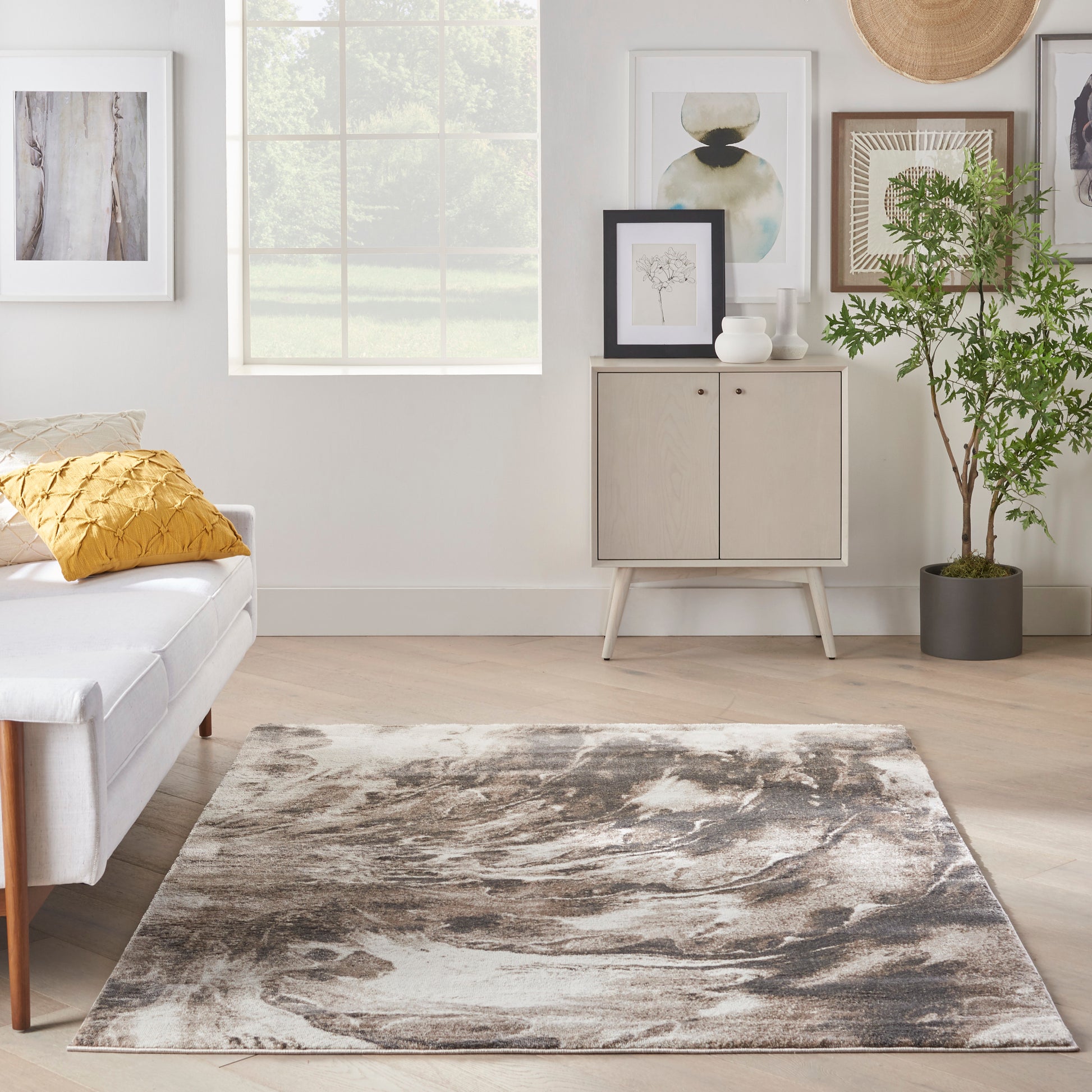 Rectangular abstract gray-beige area rug, 5' x 7', on light wood floor in a bright Scandinavian living room.