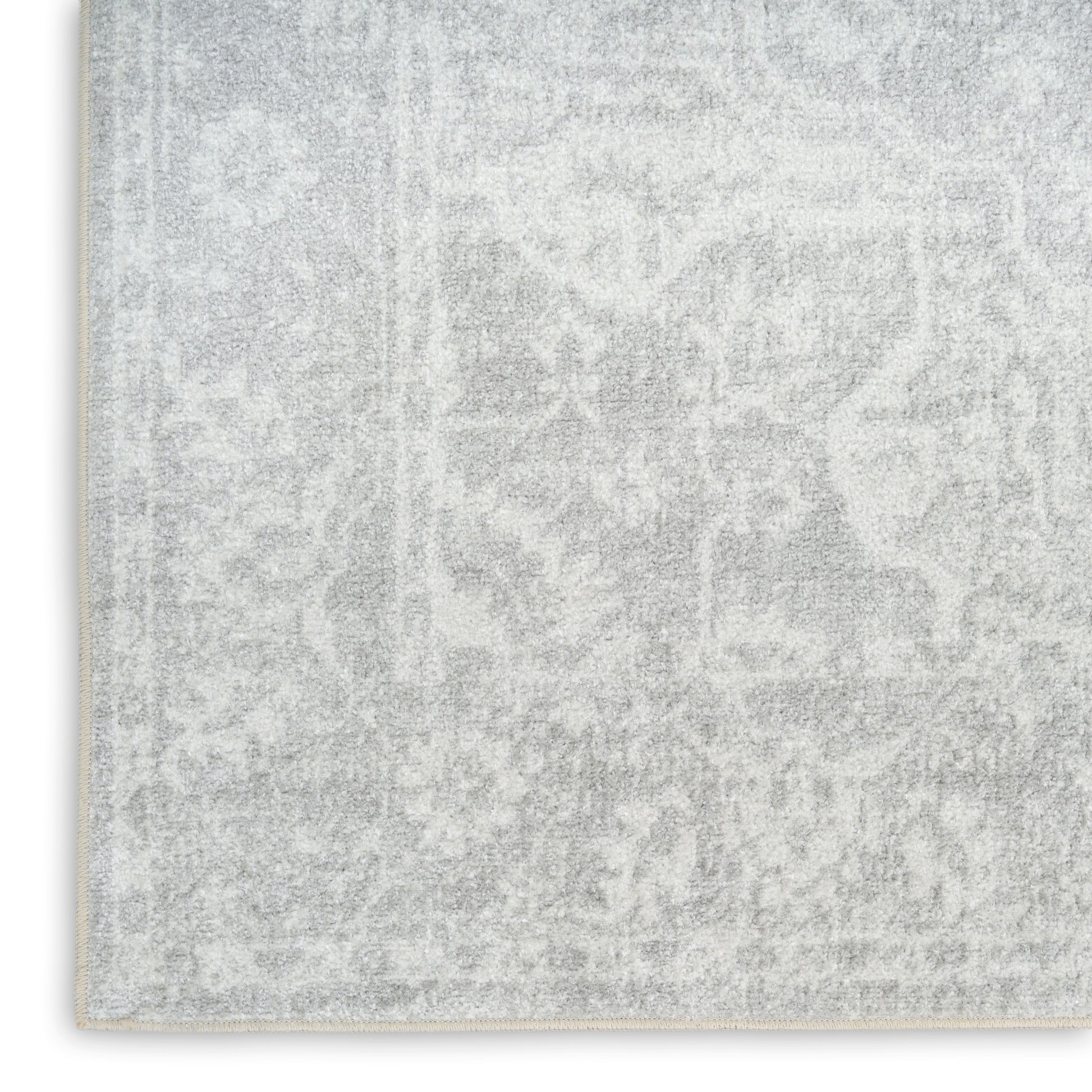 Rectangular light gray rug with faded damask pattern and pale border; plush texture for living areas.