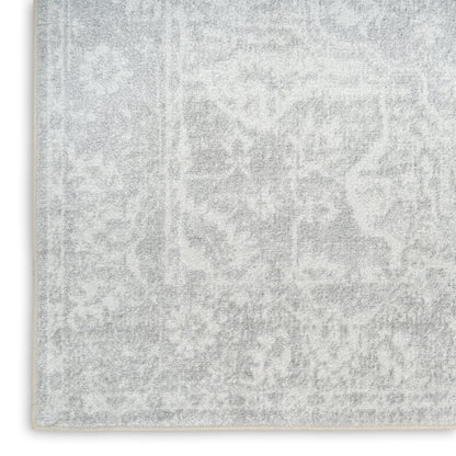Rectangular light gray rug with faded damask pattern and pale border; plush texture for living areas.
