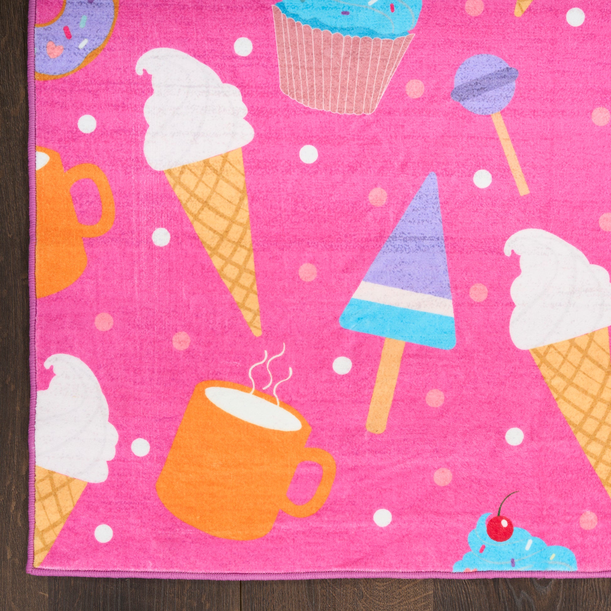 Soft pink kids rug with a dessert-print pattern featuring ice cream cones, cupcakes, mugs, popsicles and sprinkles.