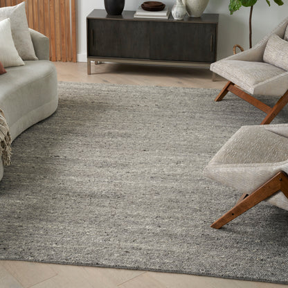 Living room with a textured gray rug, light beige sofa and wood-framed lounge chairs, and a dark wood mid-century console.