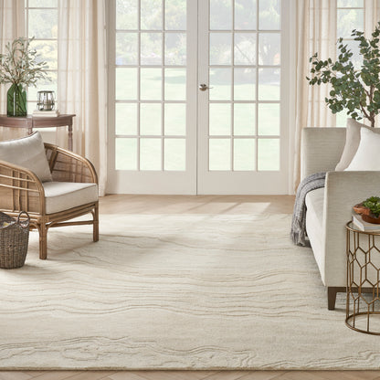 Bright living room with cream rug featuring subtle wavy pattern, wicker chair, neutral sofa, and glass French doors.