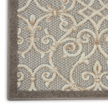 Close-up of a beige damask rug with cream scrolling pattern on gray-taupe background and dark border.