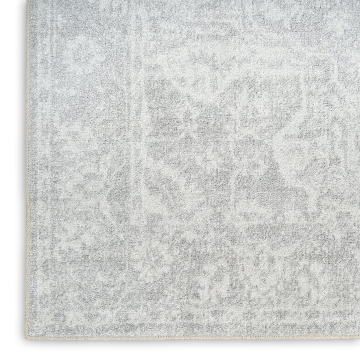 Light gray distressed patterned area rug with subtle damask motifs, soft plush texture, edge visible.