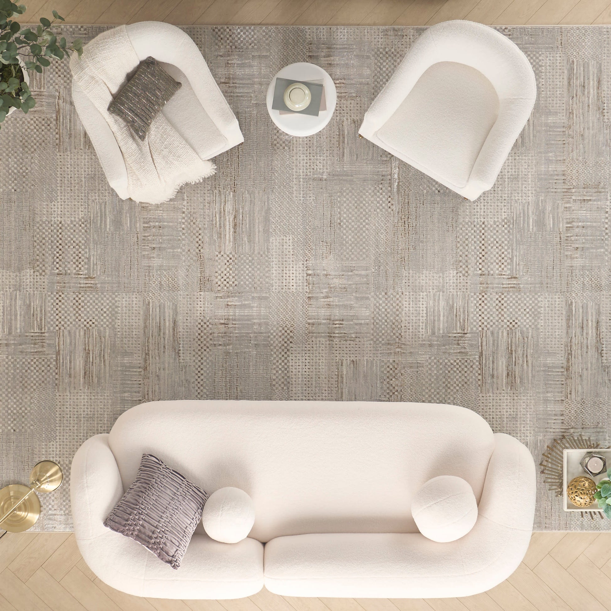 Cream sofa with gray pillow and round white cushions, two white armchairs, and a gray textured rug in a modern living room.