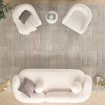 Cream sofa with gray pillow and round white cushions, two white armchairs, and a gray textured rug in a modern living room.