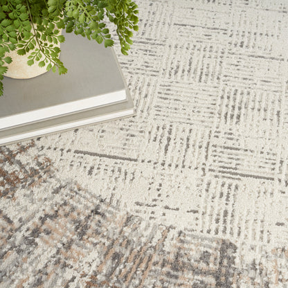 Green fern in a light ceramic pot atop a stack of books on a textured beige-gray geometric rug.
