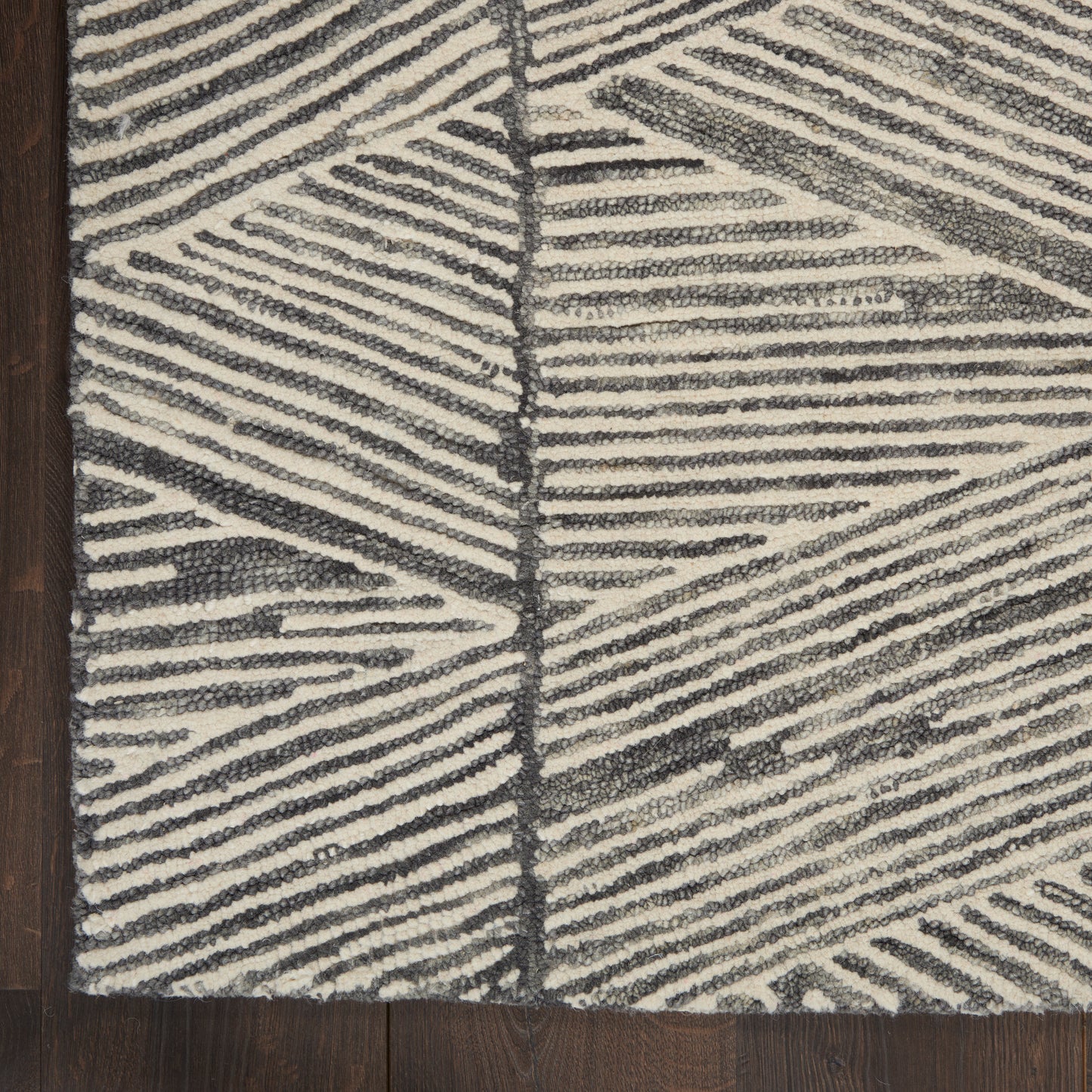 Ivory and charcoal woven rug with bold diagonal striped geometric pattern and plush looped pile on dark wood floor.