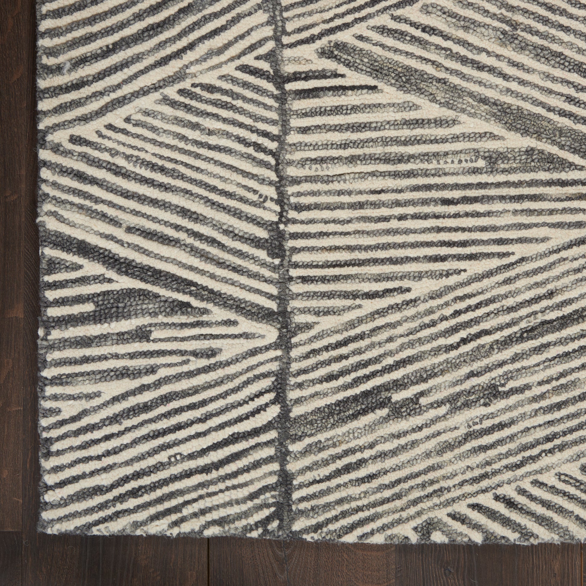 Ivory and charcoal woven rug with bold diagonal striped geometric pattern and plush looped pile on dark wood floor.