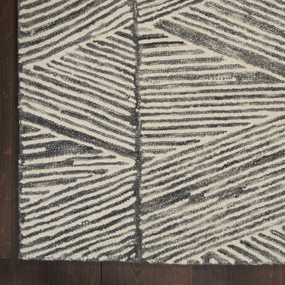 Ivory and charcoal woven rug with bold diagonal striped geometric pattern and plush looped pile on dark wood floor.
