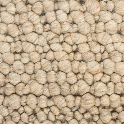 Beige boucle wool rug close-up with chunky looped tufts and textured surface.