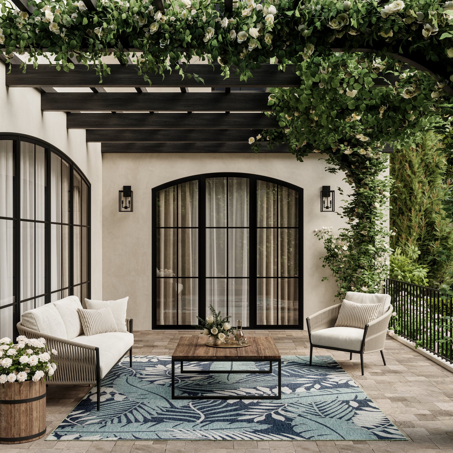 Cozy outdoor seating on a patio: cream cushioned chairs, wooden coffee table, blue leaf rug, arched glass doors, ivy pergola.