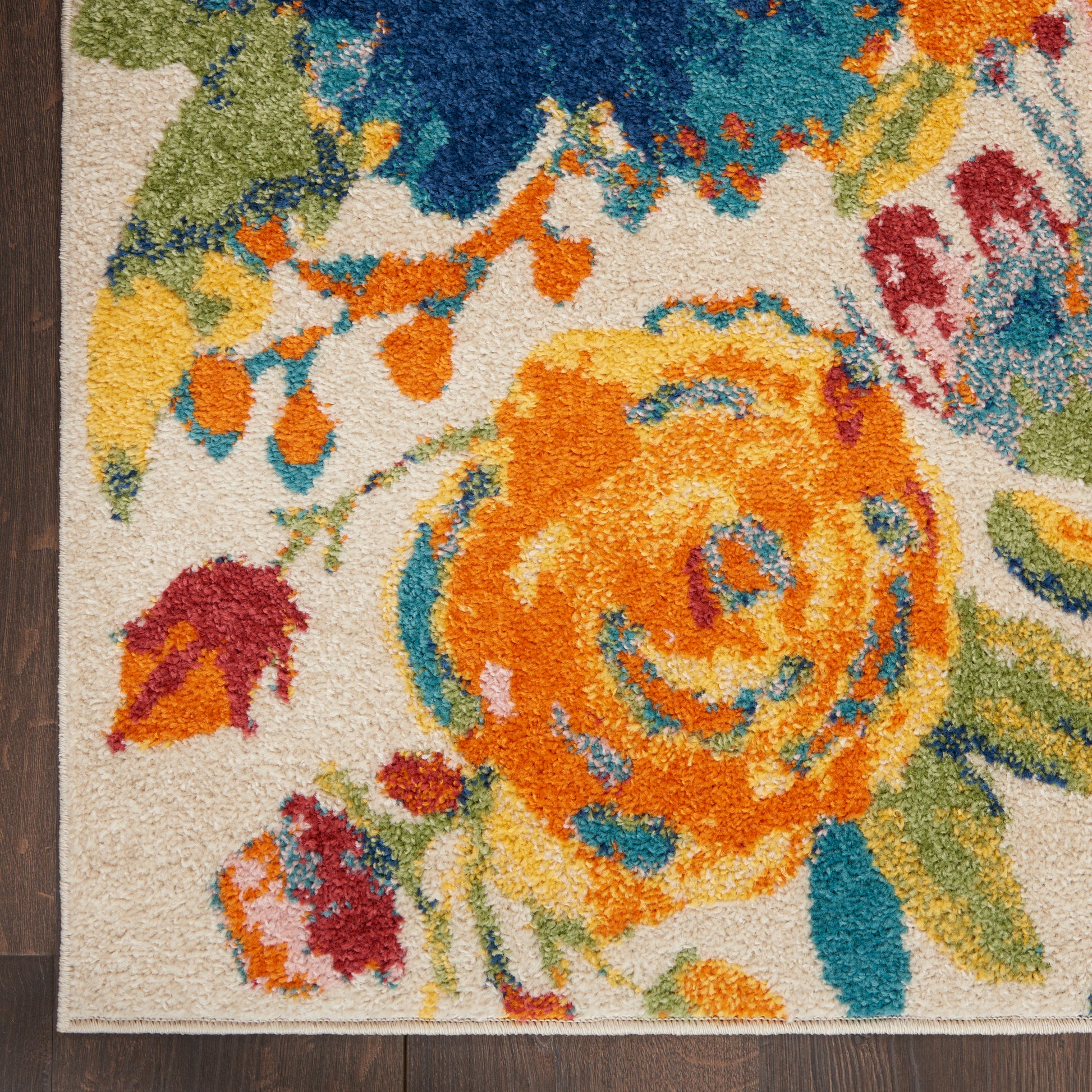 Colorful floral-patterned rug with a large orange bloom and teal accents on a beige background; textured pile.