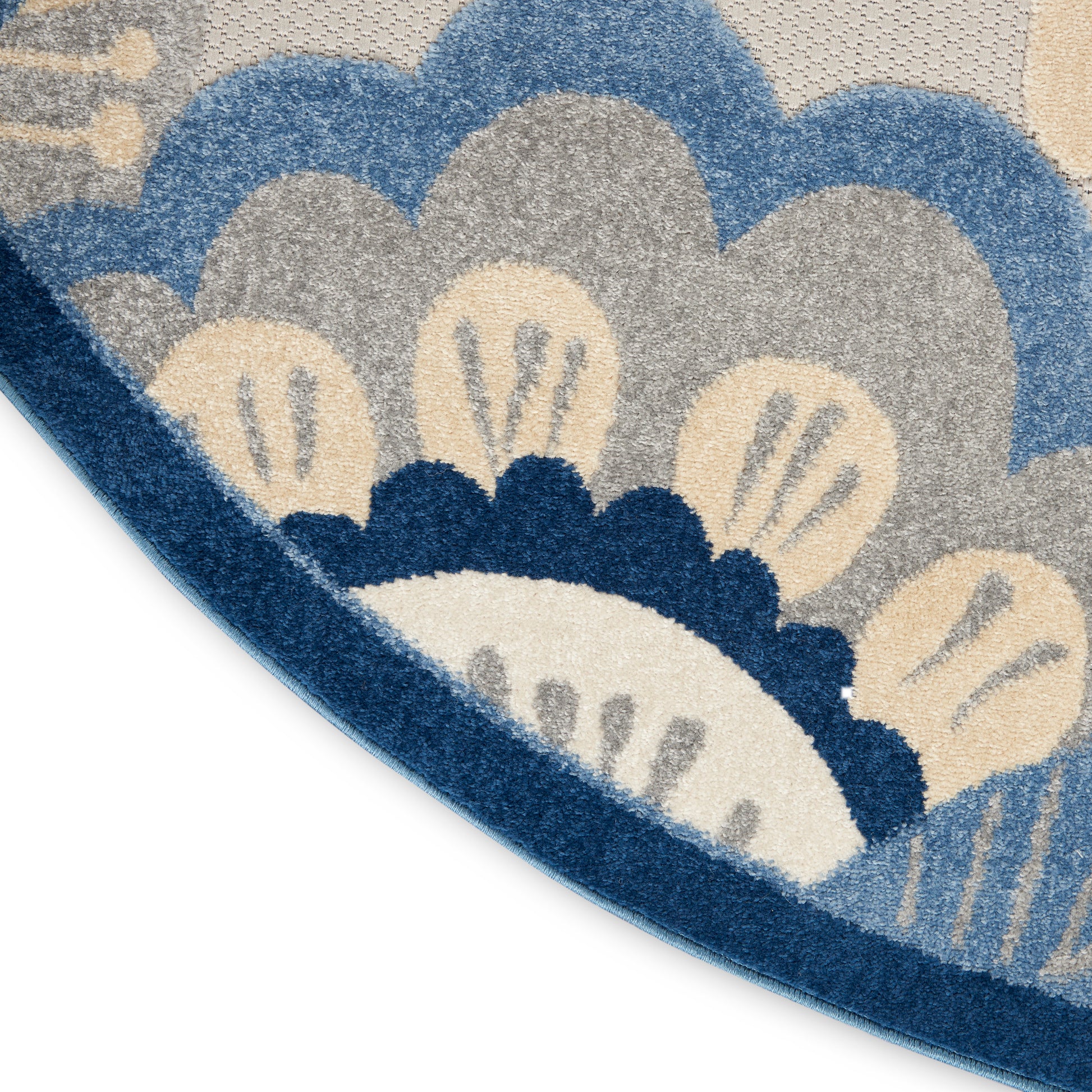 Close-up of a tufted rug with blue, gray and beige floral pattern and a curved dark blue border.