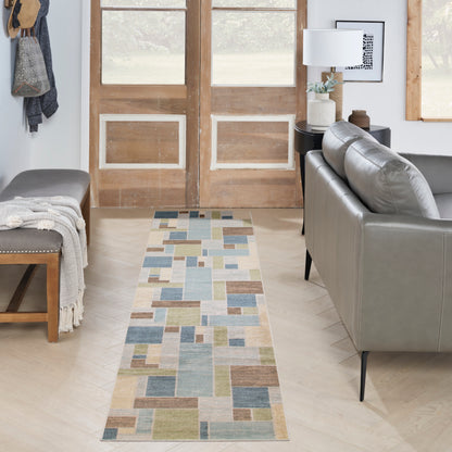 Pastel geometric patchwork rug runner in blues, greens, and beiges on light wood floor in modern living room.