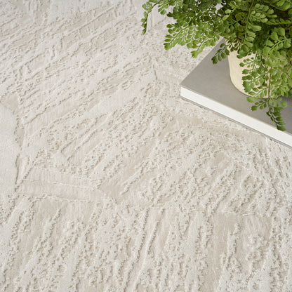 Beige textured rug with abstract raised pattern; green fern on a gray hardcover book at the corner.