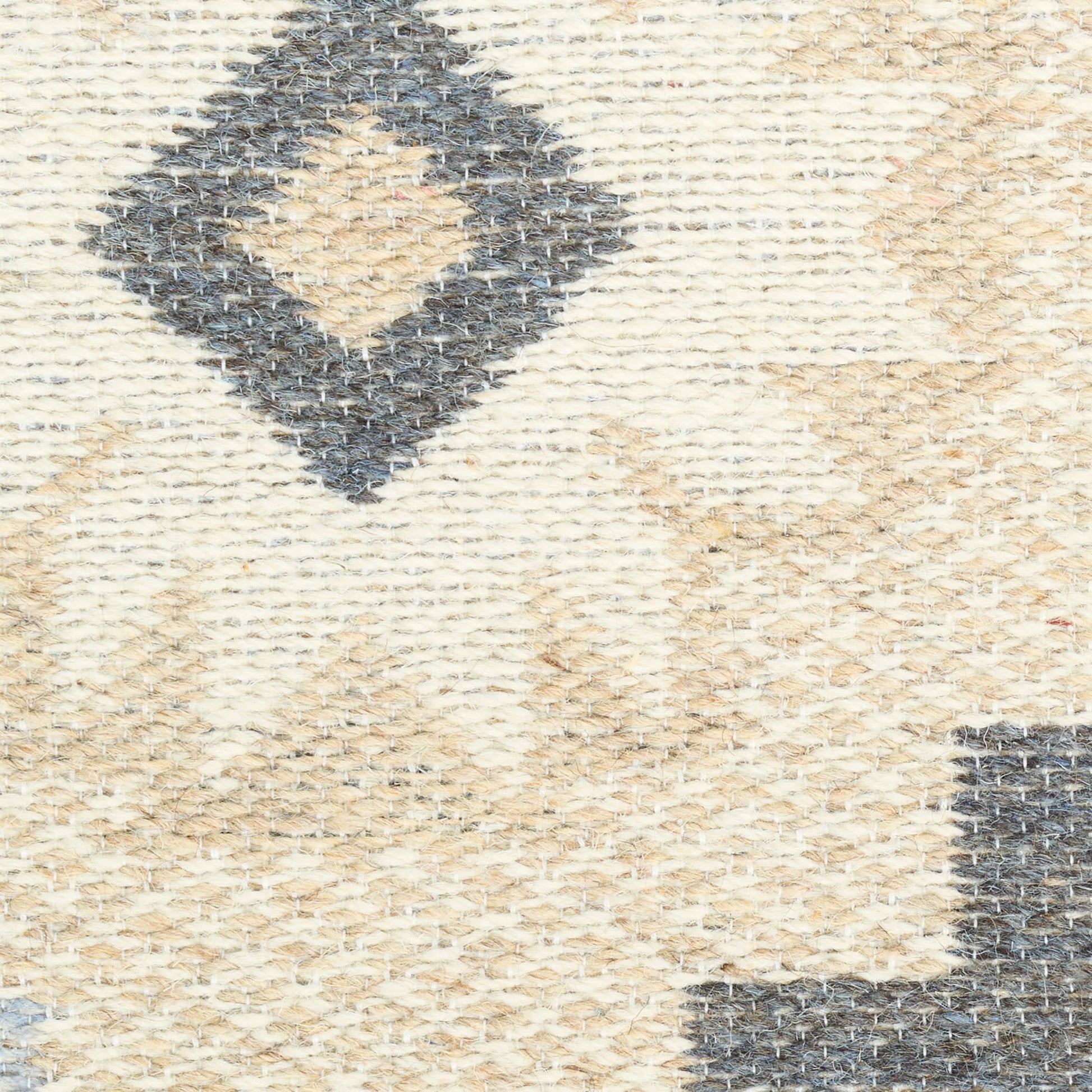 Beige woven rug with dark blue diamond motifs; textured, geometric, boho-style decor.
