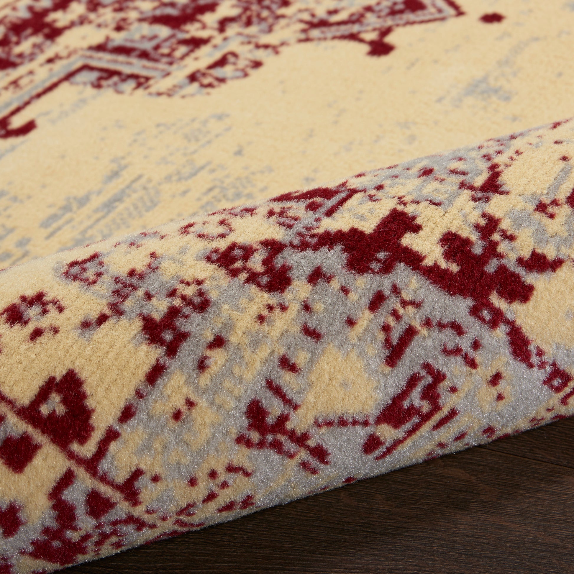 Beige cream oriental rug with red geometric motifs and blue-gray accents; thick plush pile on dark wood.