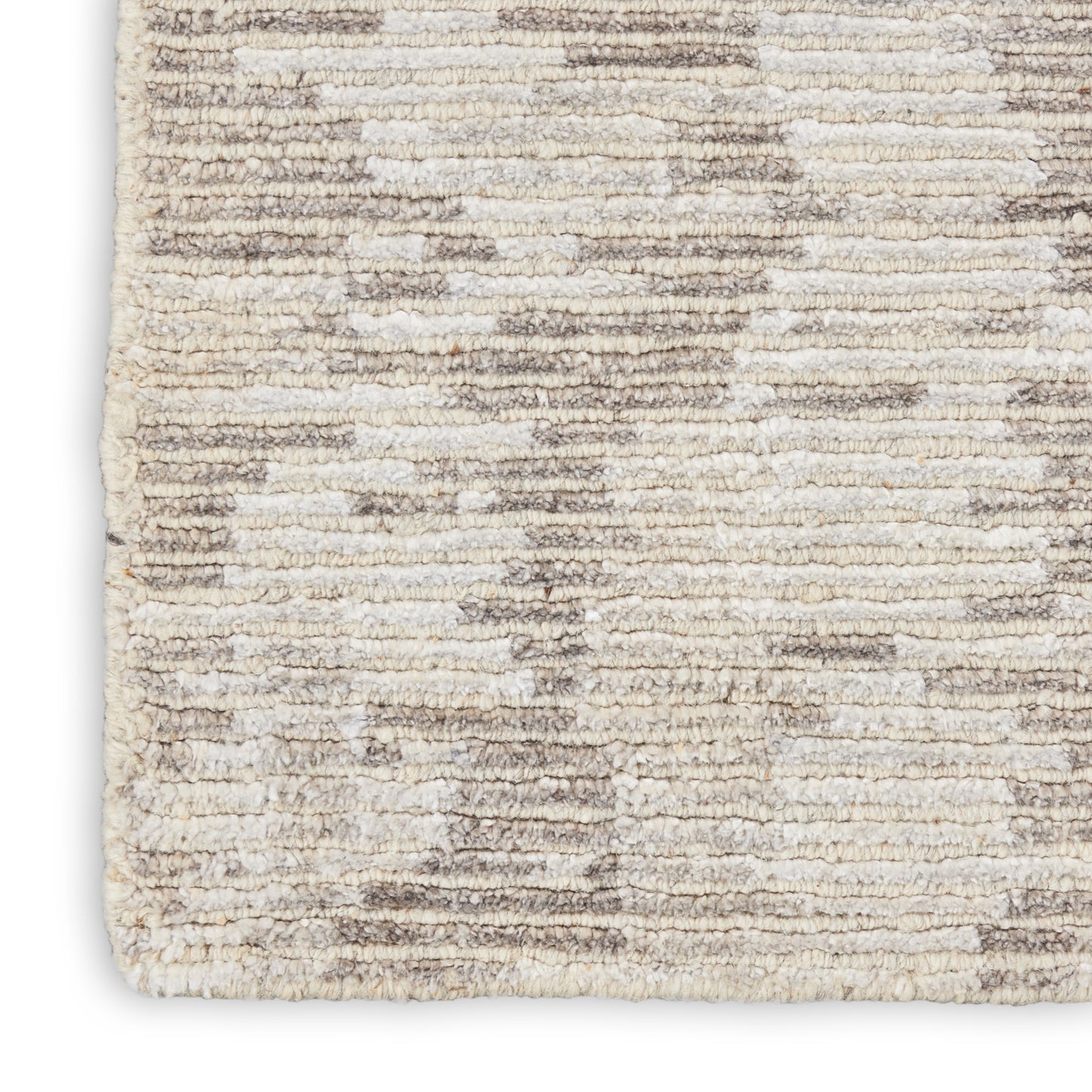 Close-up of a cream-taupe shag rug with plush pile and a subtle abstract geometric pattern.