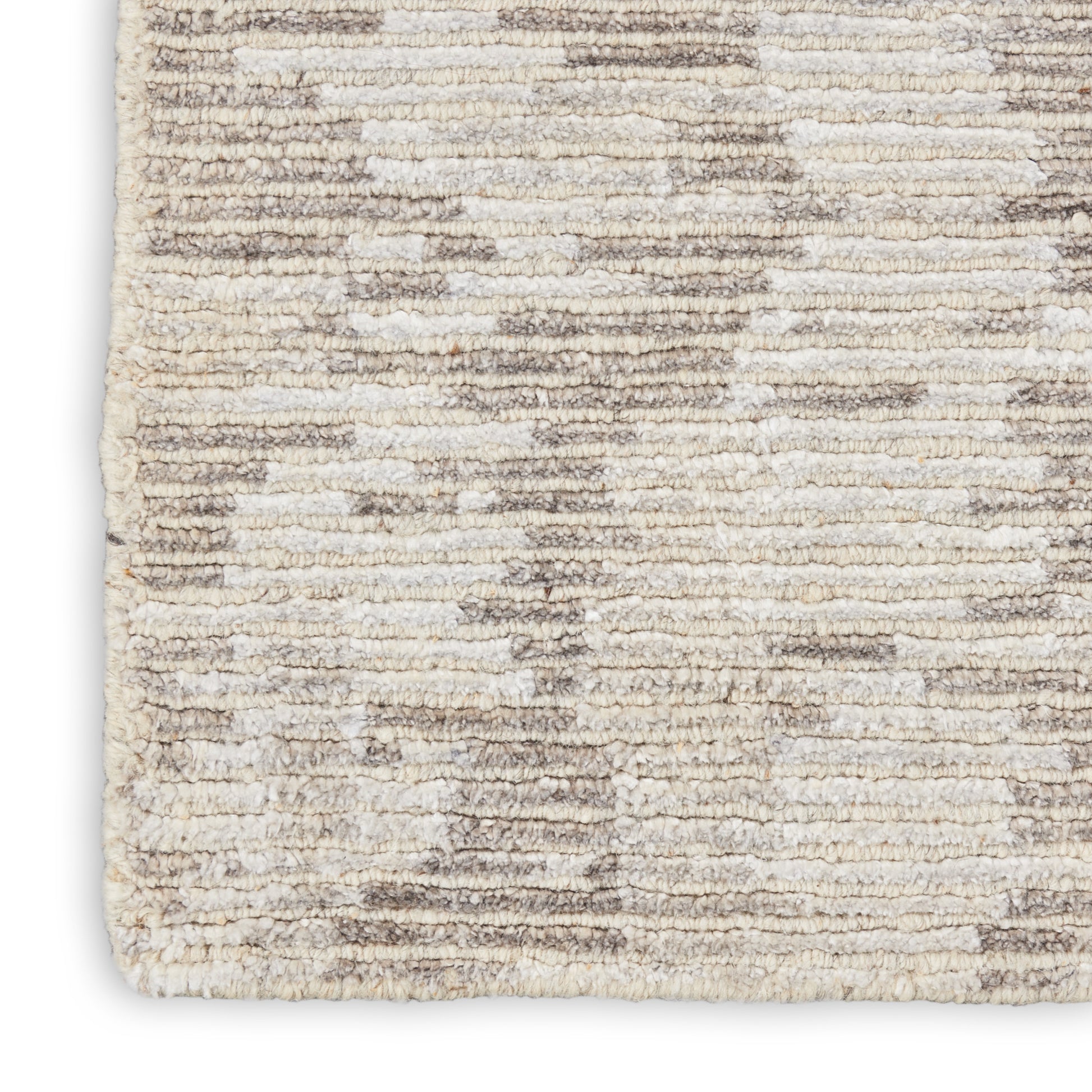 Close-up of a cream-taupe shag rug with plush pile and a subtle abstract geometric pattern.