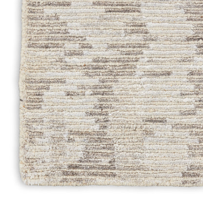 Close-up of a cream-taupe shag rug with plush pile and a subtle abstract geometric pattern.