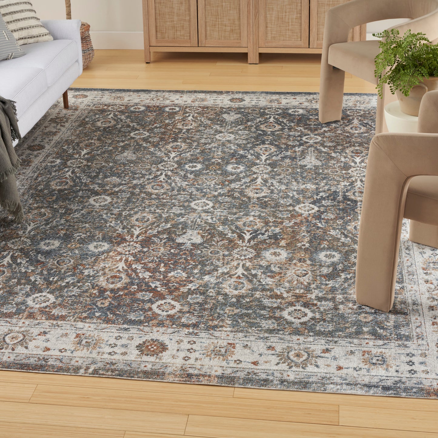 Traditional blue-gray rug with cream medallions on light hardwood, paired with beige upholstered chairs.