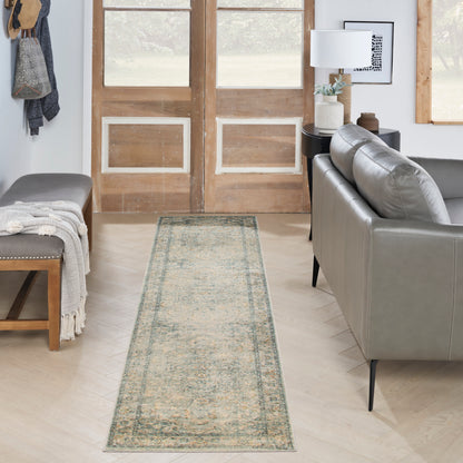 Distressed vintage-style runner rug in muted teal and beige along doorway; grey sofa, wooden bench, throw blanket.