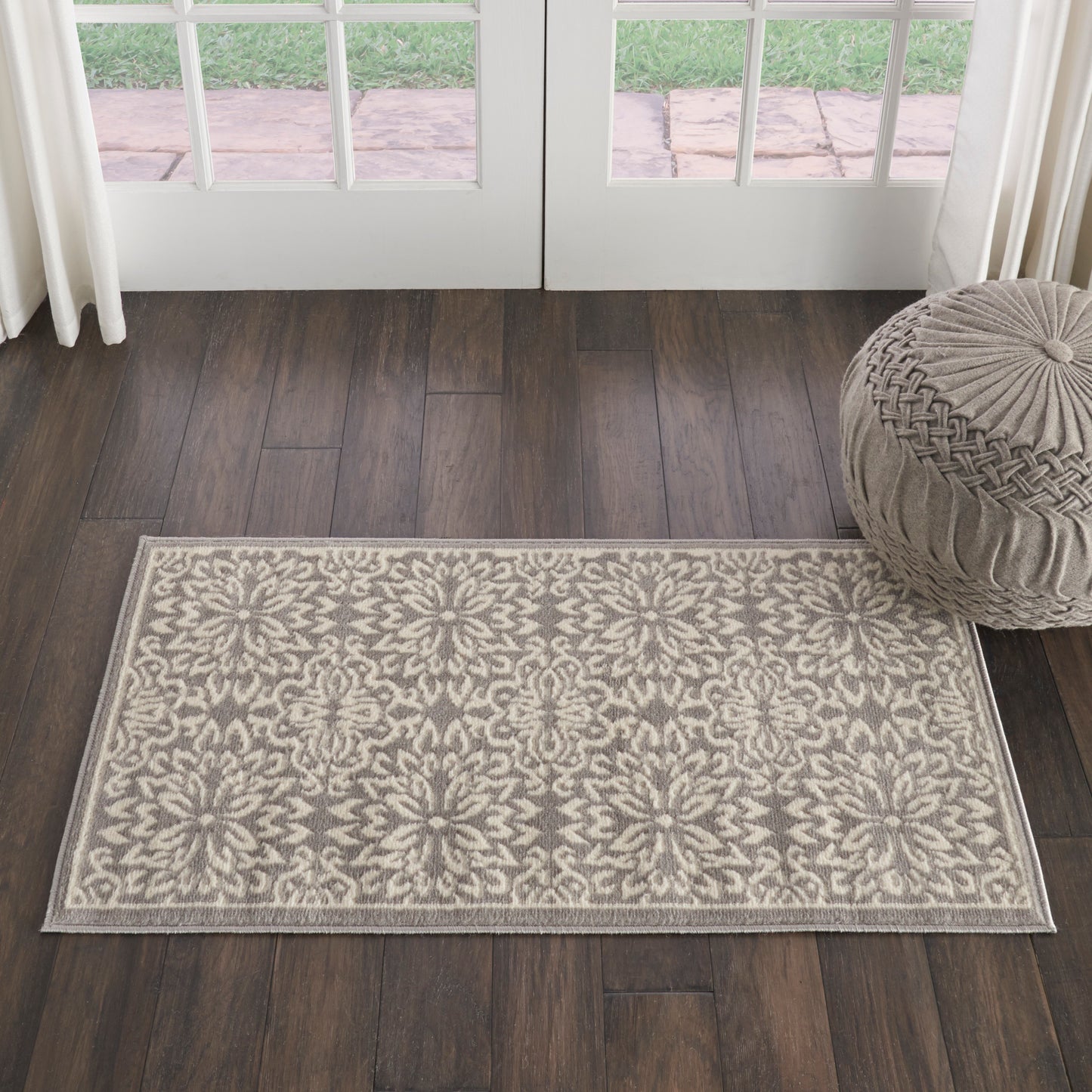 Cream & beige damask floral flat-weave rug, rectangular, on dark wood flooring near glass doors.
