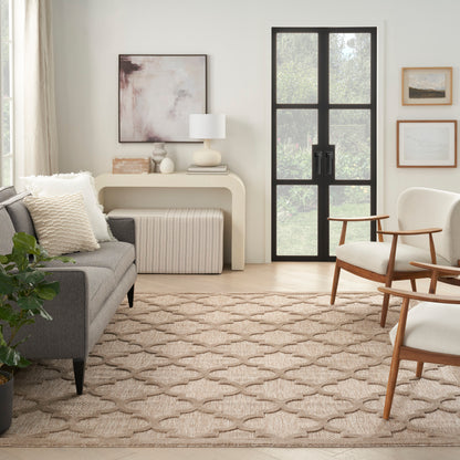 Neutral living room with gray fabric sofa, beige geometric rug, mid-century wooden chairs, black-framed glass door, natural light.