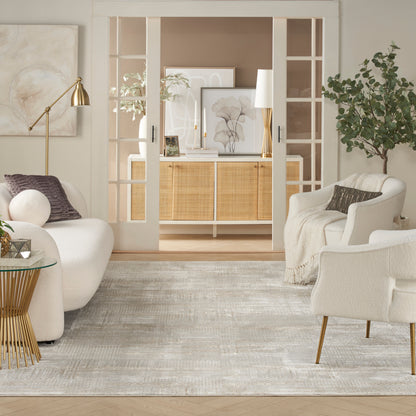 Bright beige and white living room with curved white sofas, gold lamp, glass side table, neutral rug, and open French doors.