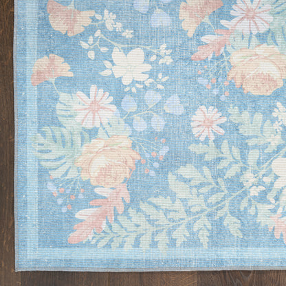 Blue floral rug with pastel pink and white blossoms and leafy pattern, bordered edge.