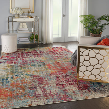 Colorful abstract area rug in a bright living room with gold lattice chair, glass bookshelf, potted plant, and cream seating.