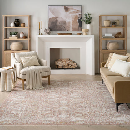 Neutral living room with white fireplace, wooden bookshelves, beige armchair, tan sofa, pink rug, and abstract art above mantel.