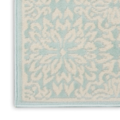 Close-up of pale blue & cream woven rug with a snowflake floral pattern and light blue border.
