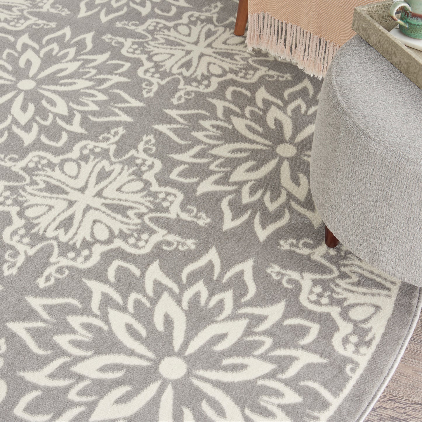 Grey area rug with large white floral/mandala motif; plush texture in living room setting.