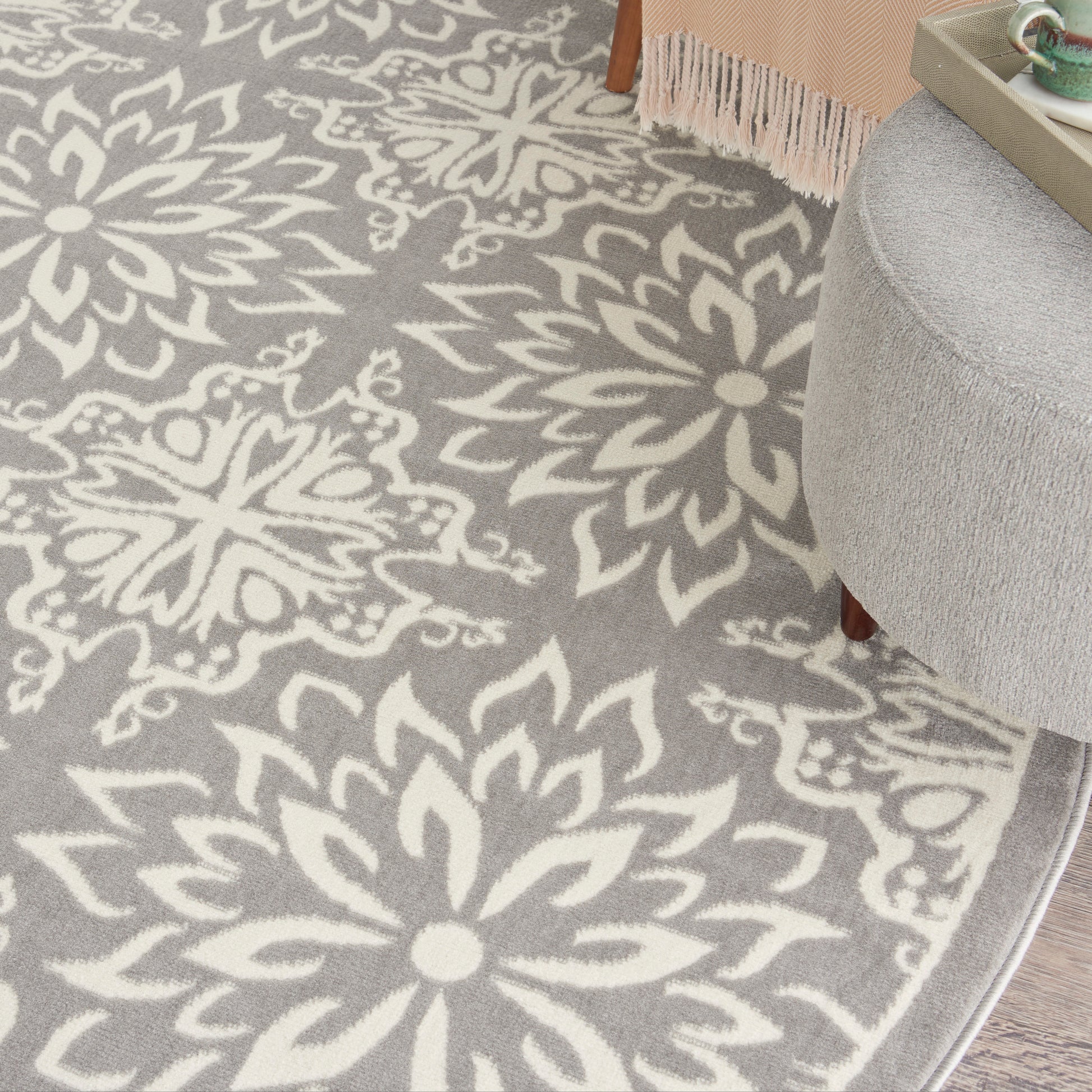 Grey area rug with large white floral/mandala motif; plush texture in living room setting.