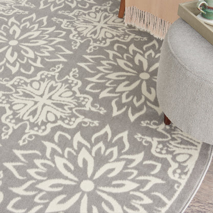 Grey area rug with large white floral/mandala motif; plush texture in living room setting.