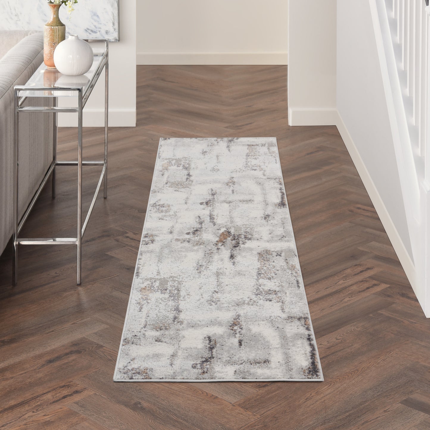 Long neutral runner rug with an abstract gray pattern in a modern hallway beside a glass console.