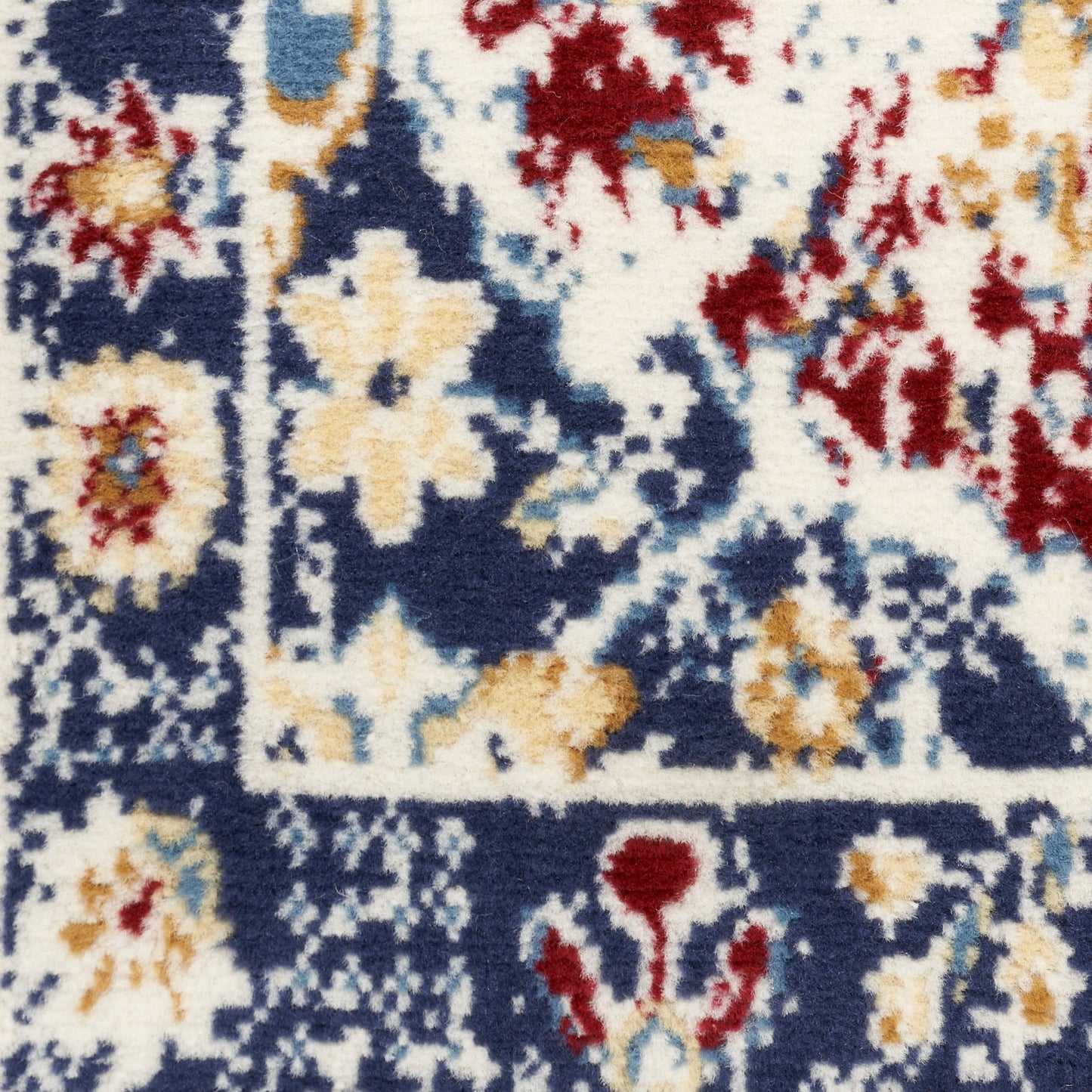 Close-up of a Persian-style rug runner with a navy field, ivory/gold floral motifs, red accents, and a wool-like pile.