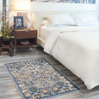 White bed with cream bedding, wood nightstand, lamp, plant, framed photo; blue and ivory bohemian rug on gray floor, 3' x 5'.