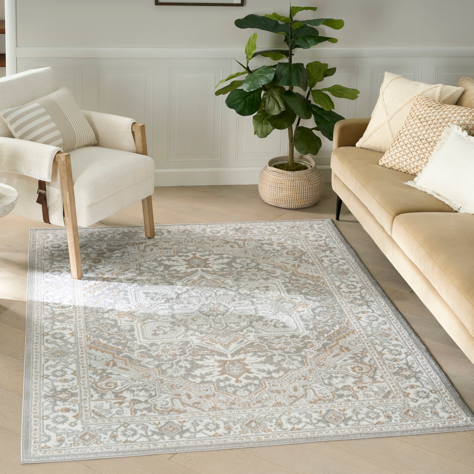 Ivory-gray oriental-style rug with beige medallion pattern on light wood floor, styled living room with cream chair and beige sofa.