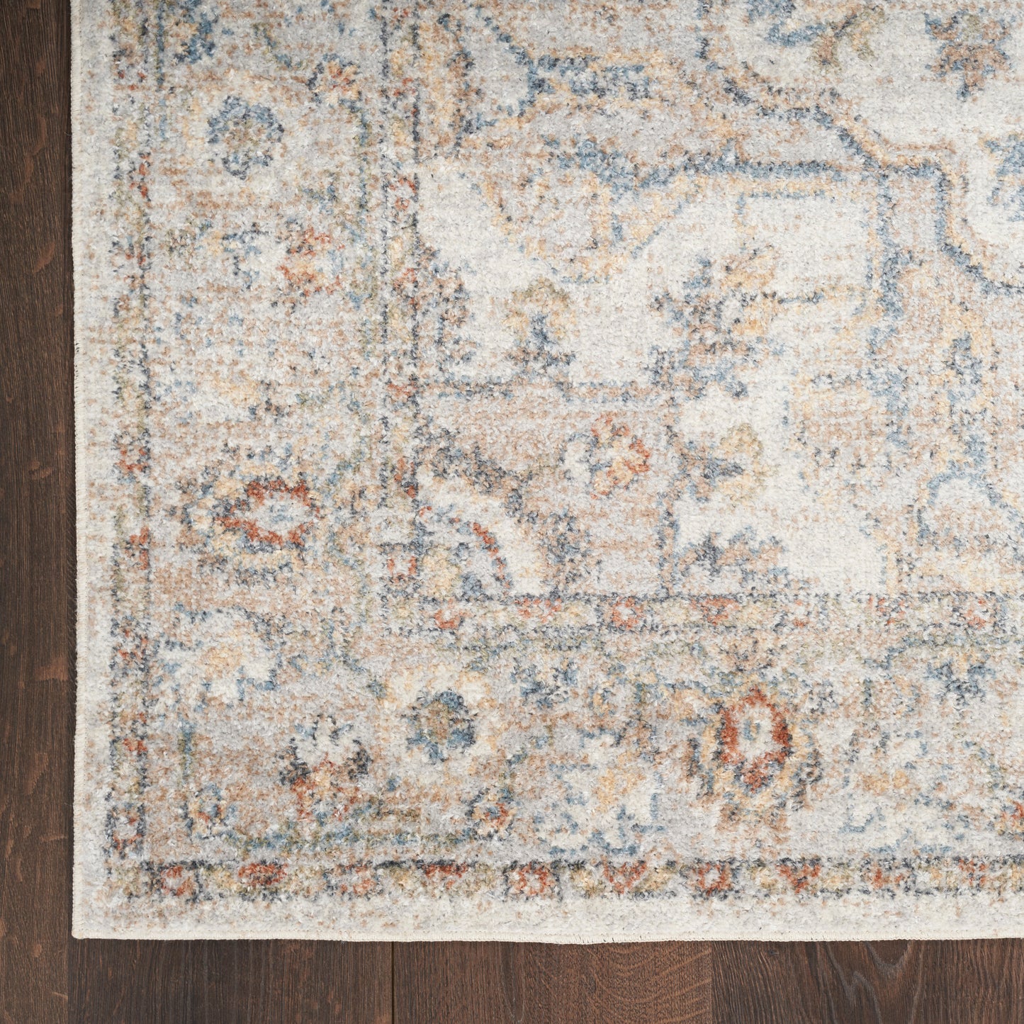 Cream distressed oriental area rug with blue and orange details on dark wood floor.