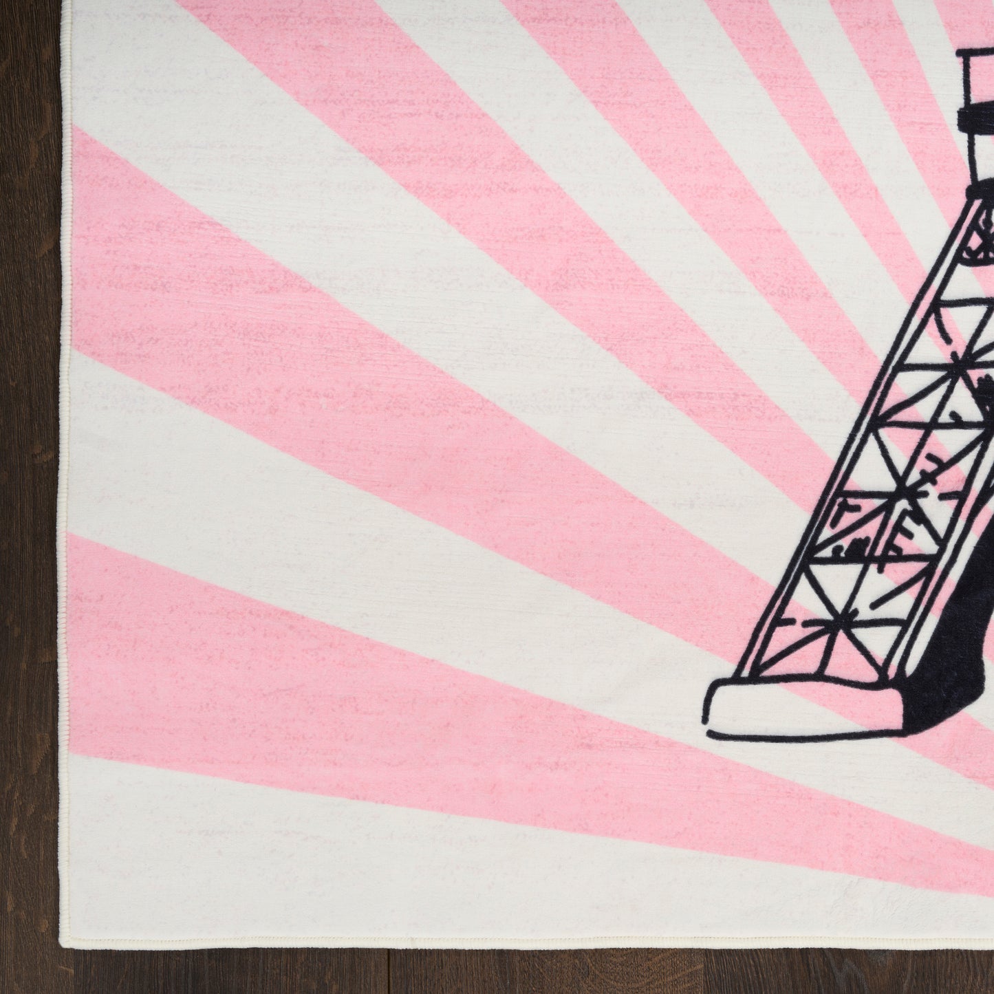 Beige kids' rug with pink sunburst rays and a black line-art Eiffel Tower on the right edge.